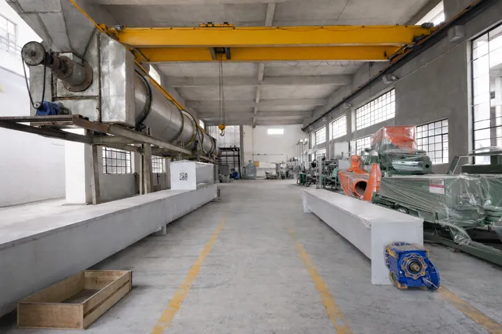 A rotary dryer drum suspended from the overhead crane